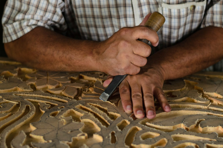 Close-up of a Tajik woodcarver bringing life to a piece of wood through meticulous carving. Old craft in Central Asia