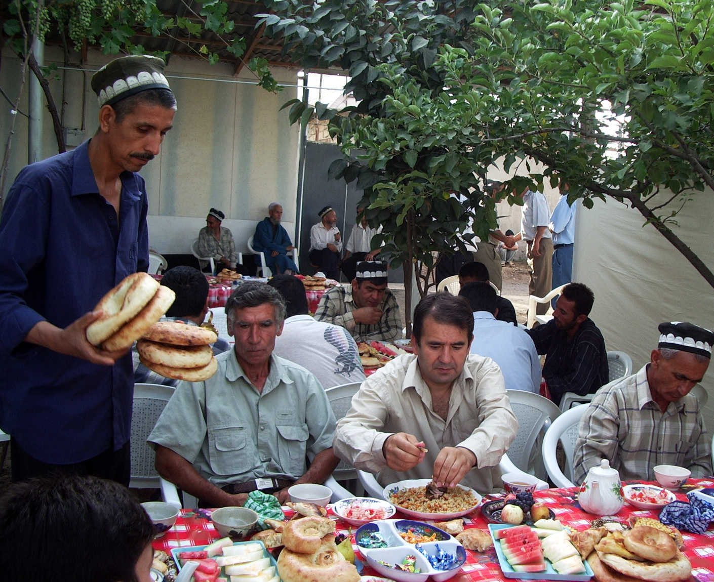 Guests enjoying a traditional oshi nahor morning plov feast, sharing food, stories, and laughter in an outdoor communal gathering