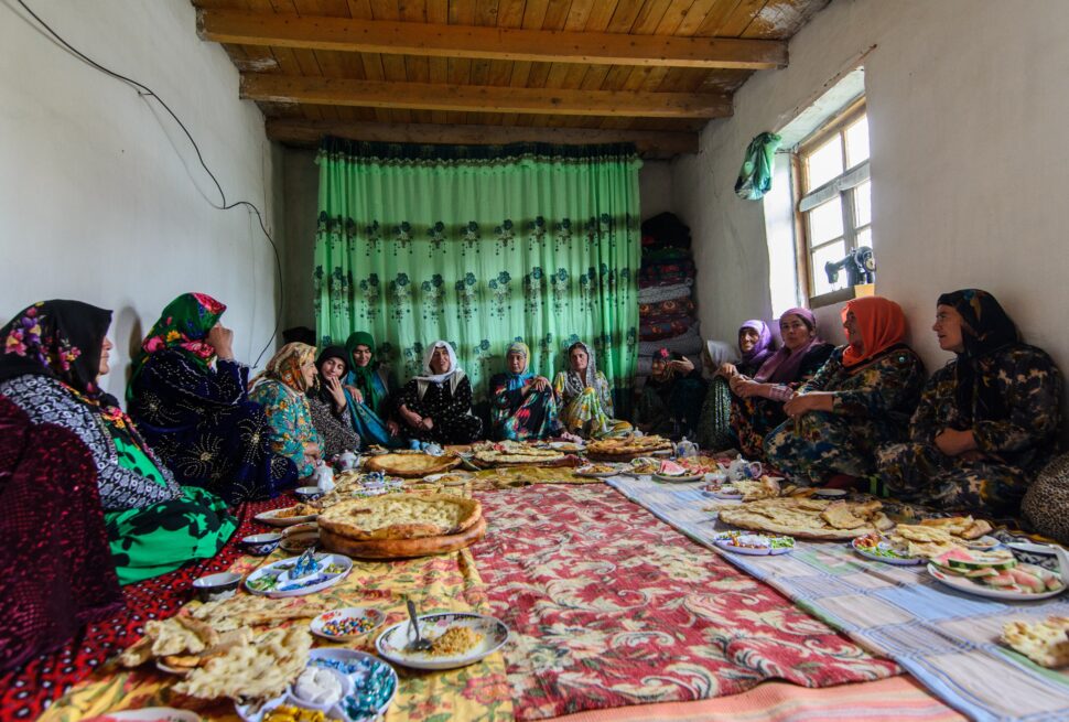 Tajik women in traditional dress sharing a festive meal with traditional bread and plov on dastarkhon