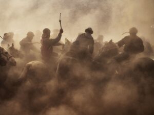 Horsemen battle through dust during an intense Buzkashi match in Tajikistan, showcasing the sport's raw energy and tradition